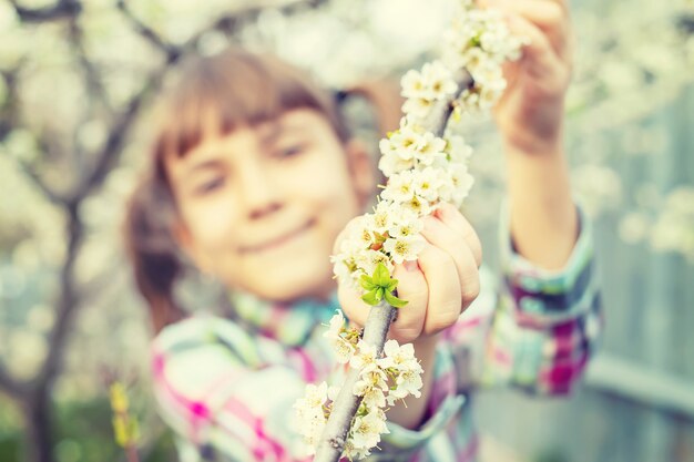 Foto un bambino nel giardino di alberi in fiore. messa a fuoco selettiva.