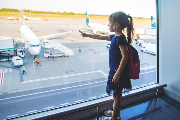 A child girl at the airport looks at the planes