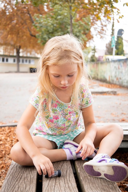 子供の女の子の金髪就学前の年齢は、ベンチに座っています。