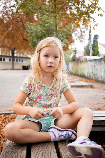 子供の女の子の金髪就学前の年齢は、ベンチに座っています。