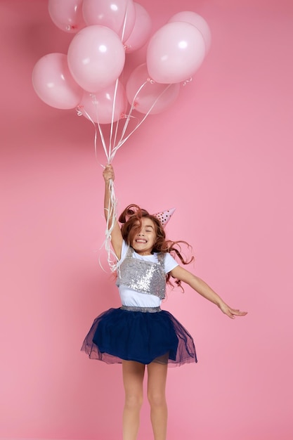 Child girl celebrating with pastel pink air balloons