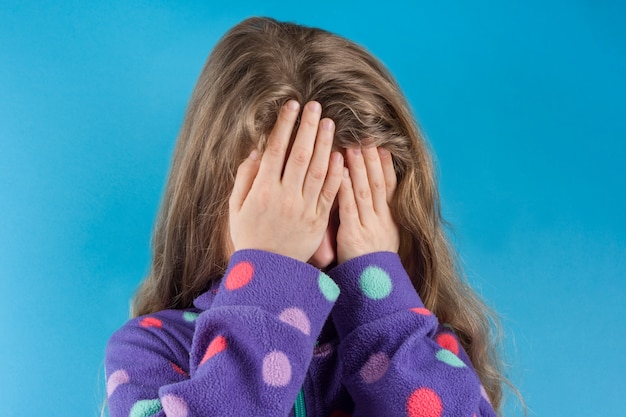 Child girl covered her face with hands