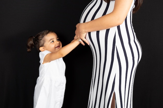 child girl daughter hug pregnant belly mother woman