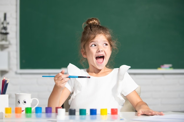 Child girl drawing with coloring pens paintind Portrait of adorable little girl smiling happily whil