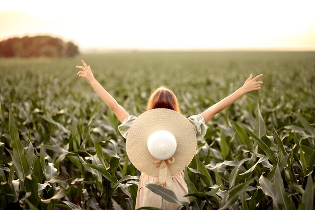 Photo child girl in a dress and hat stands in a cornfield