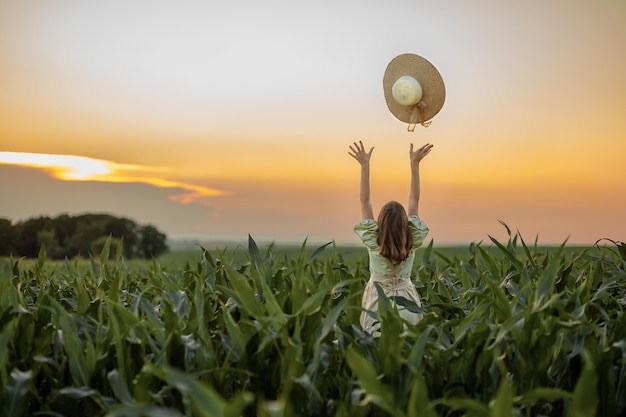 Photo child girl in a dress and hat stands in a cornfield