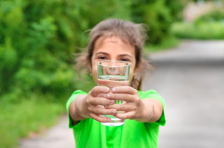 Photo child girl drinks water from a glass. selective focus. kid.