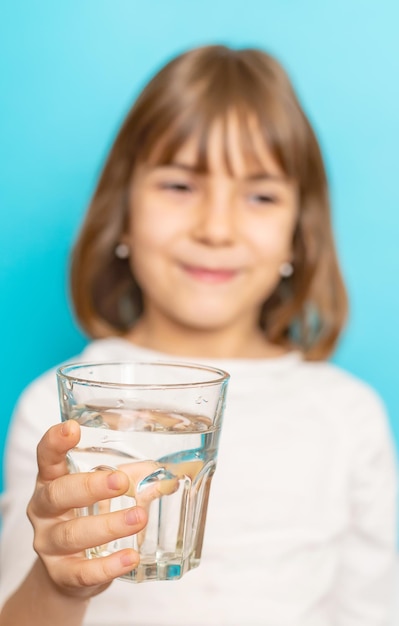 子供の女の子はガラスから水を飲む選択的な焦点