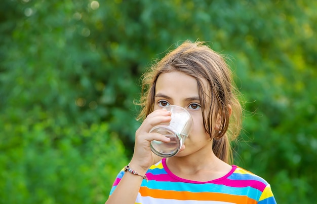 Child girl drinks water from a glass. 