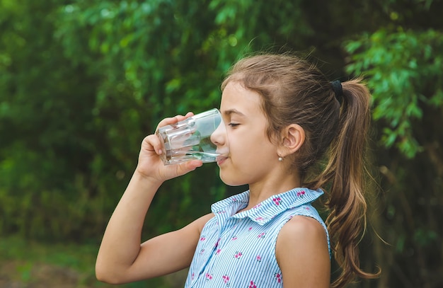 Child girl drinks water from a glass. 