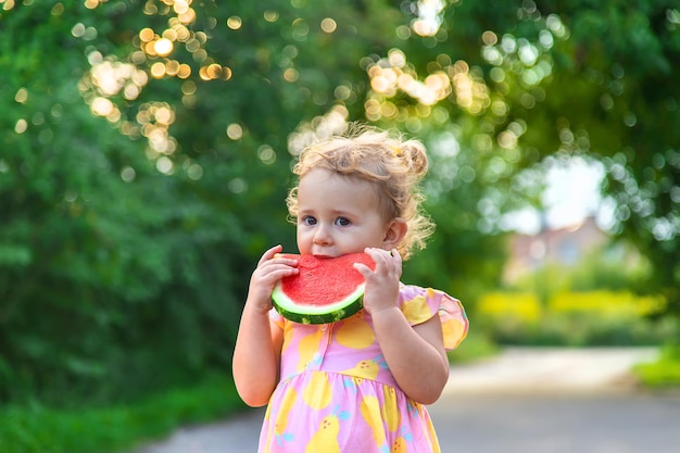 La ragazza del bambino mangia l'anguria in estate messa a fuoco selettiva