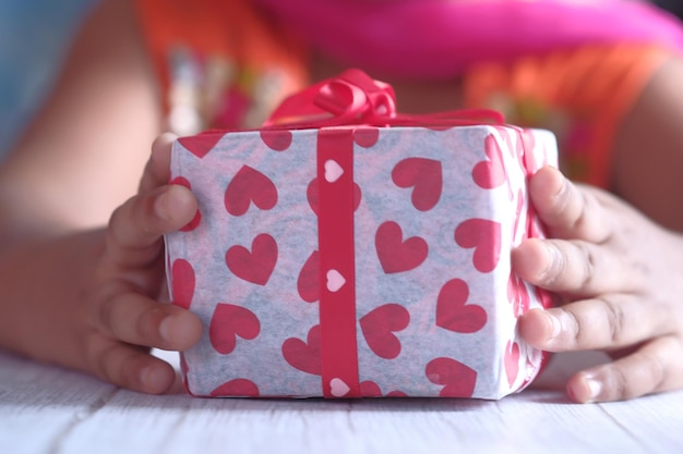 Child girl hand holding gift on table