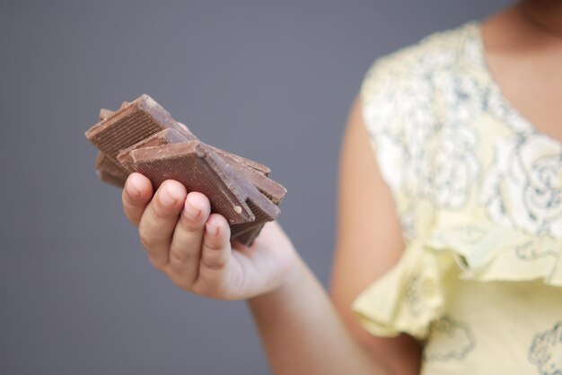 子供の女の子の手は灰色の背景にダークチョコレートを選ぶ