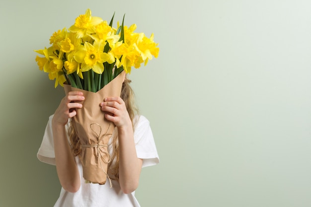 Child girl holding bouquet of yellow flowers.