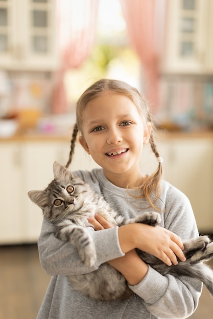 Child girl holding a fluffy kitten in her arms