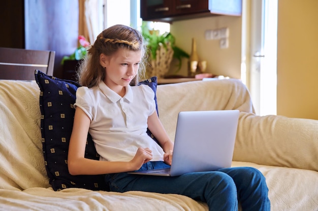 Child girl at home on the sofa with a laptop