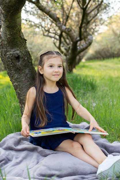 子供の女の子が公園で本を読んでいる