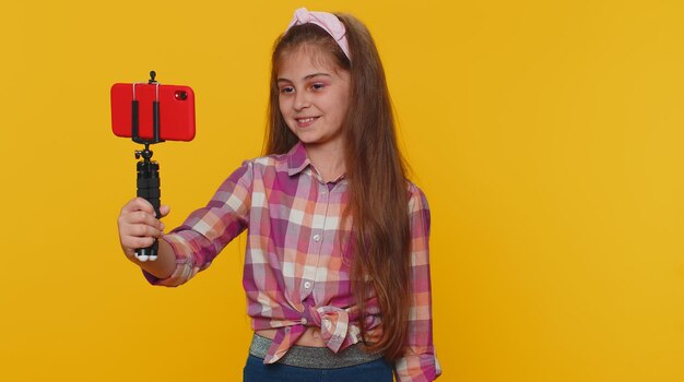 Child girl kid blogger taking selfie on smartphone communicating video call online with subscribers