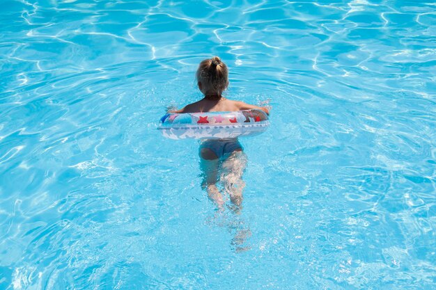 Child girl learn to swim with an inflatable ring in the pool