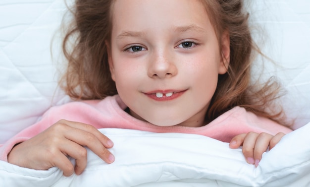 Photo child girl lies in a white bed