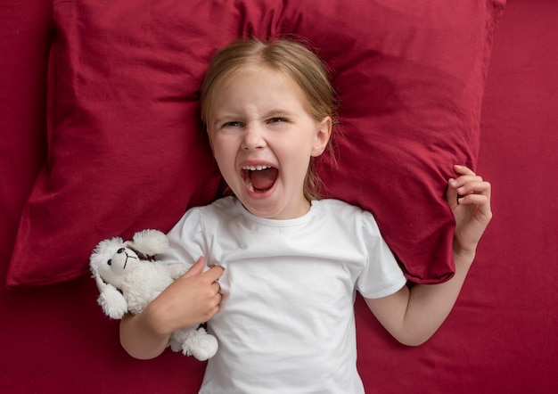 Child girl lying on the bed refuses to sleep