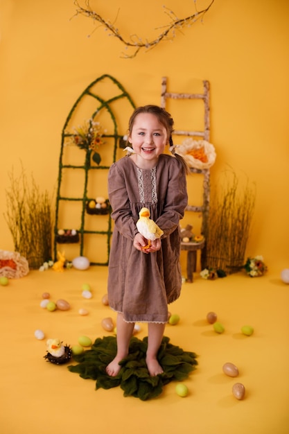 Ragazza del bambino che gioca con le uova di pasqua e la decorazione tradizionale di pasqua del pulcino nello stile rurale