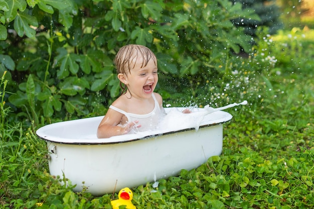 Foto una bambina in un bagno retrò si bagna nella natura e ride.