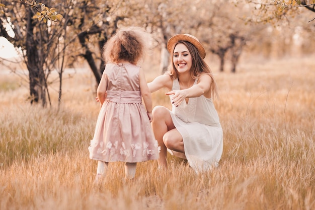 写真 屋外の牧草地で幸せな笑顔の母親に走っている子供の女の子