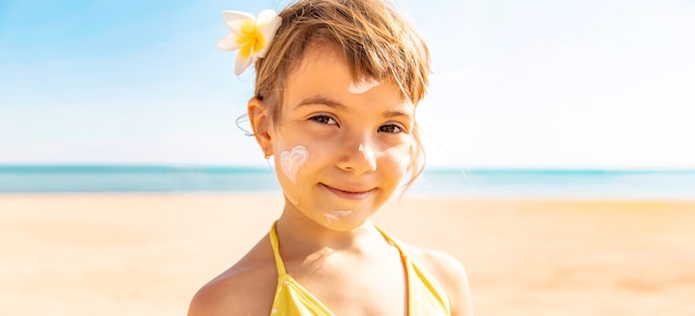La ragazza del bambino spalma la crema solare sul viso