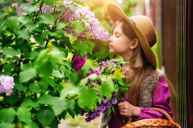 子供の女の子は春のガーデニングで花が香りを吸い込む匂いを嗅ぐ