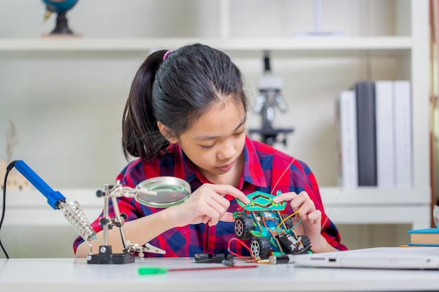 子供の女の子の学生がロボットカーを作る子供がプログラミングロボット車を学ぶ