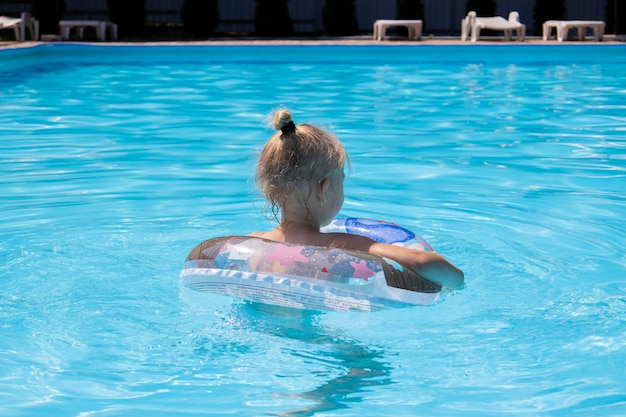 Photo child girl swims with an inflatable ring in the pool