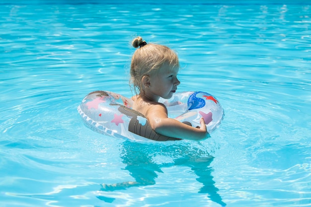 Photo child girl swims with an inflatable ring in the pool