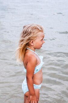 Bambina abbronzata in costume da bagno si bagna nel mare.