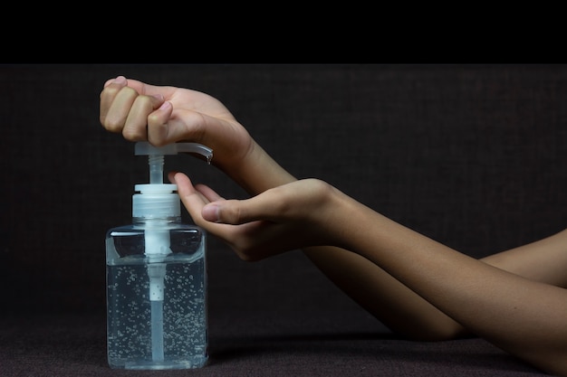 Child girl uses back of her hand to press hand sanitizer bottle to clean her hand