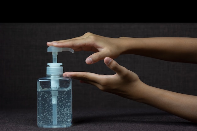 Child girl uses  her hand to press hand sanitizer bottle to clean her hand