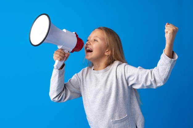 Child girl using megaphone against blue background