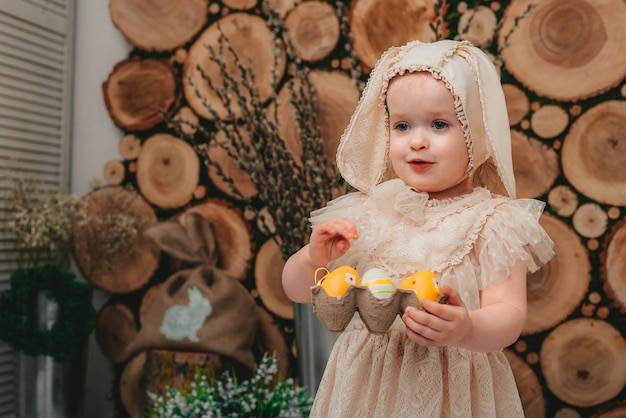 Child Girl wearing bunny ears and sitting with white ducklings on the wooden background