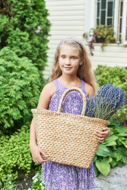 child girl with a basket of lavender in the garden in summer