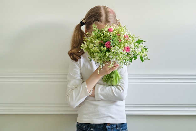 美しい春の花の花束を持つ子供の女の子