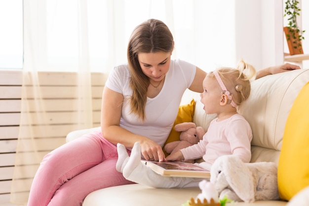 自宅で母親と人工内耳を持つ子供の女の子は、障害と聴覚障害者のコミュニティの概念を聞く