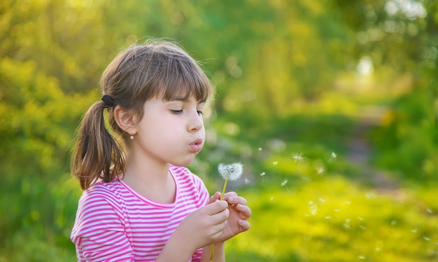 Ragazza del bambino con i denti di leone nel parco. messa a fuoco selettiva.