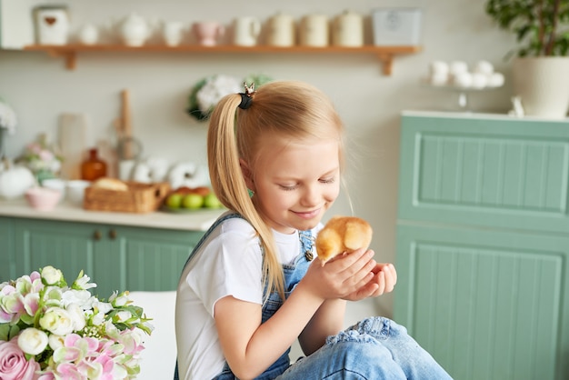 Child girl with easter eggs and chickens in kitchen. Happy easter concept. Happy family preparing for Easter.