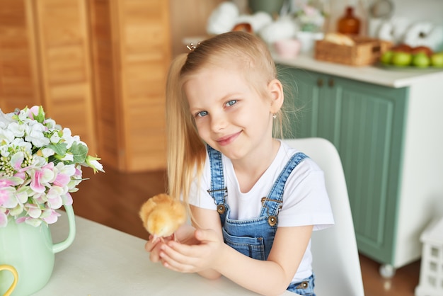 Child girl with easter eggs and chickens in kitchen. Happy easter concept. Happy family preparing for Easter.