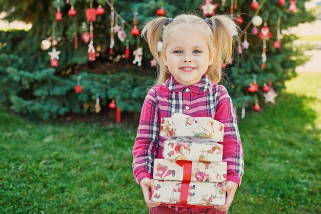 child girl  with gifts near a Christmas tree, Christmas in July on nature