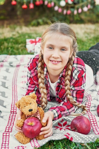 child girl with pigtails at the Christmas in July photo shoot on the background of a Christmas tree with gifts