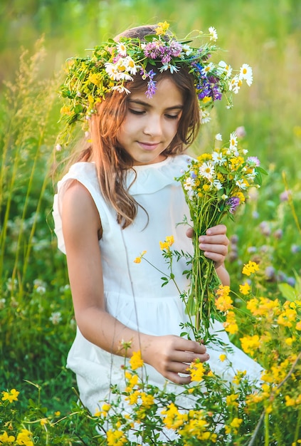 Child girl with wildflowers in summer