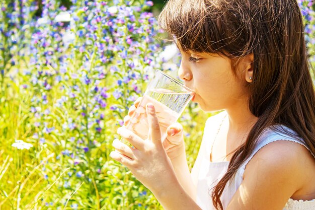 子グラスの水。セレクティブフォーカス。子供の自然