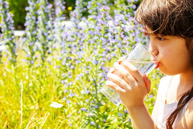 子グラスの水。セレクティブフォーカス。子供の自然