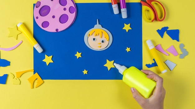 A child glues a paper star to a paper craft on the theme of space